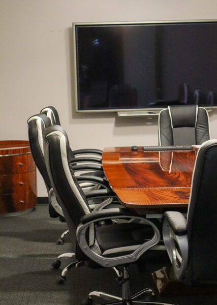 A clean empty conference room with black office chairs and a tv.