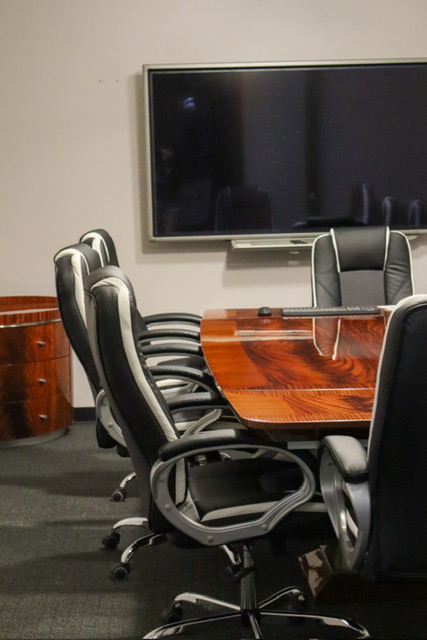 A clean empty conference room with black office chairs and a tv.