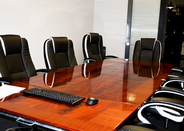 A clean wooden conference table with black office chairs.